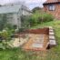Completed brick retaining wall and landscaped gravel area around greenhouse in Winchester