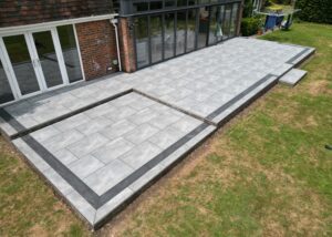 Large porcelain patio with brick retaining walls in Winchester