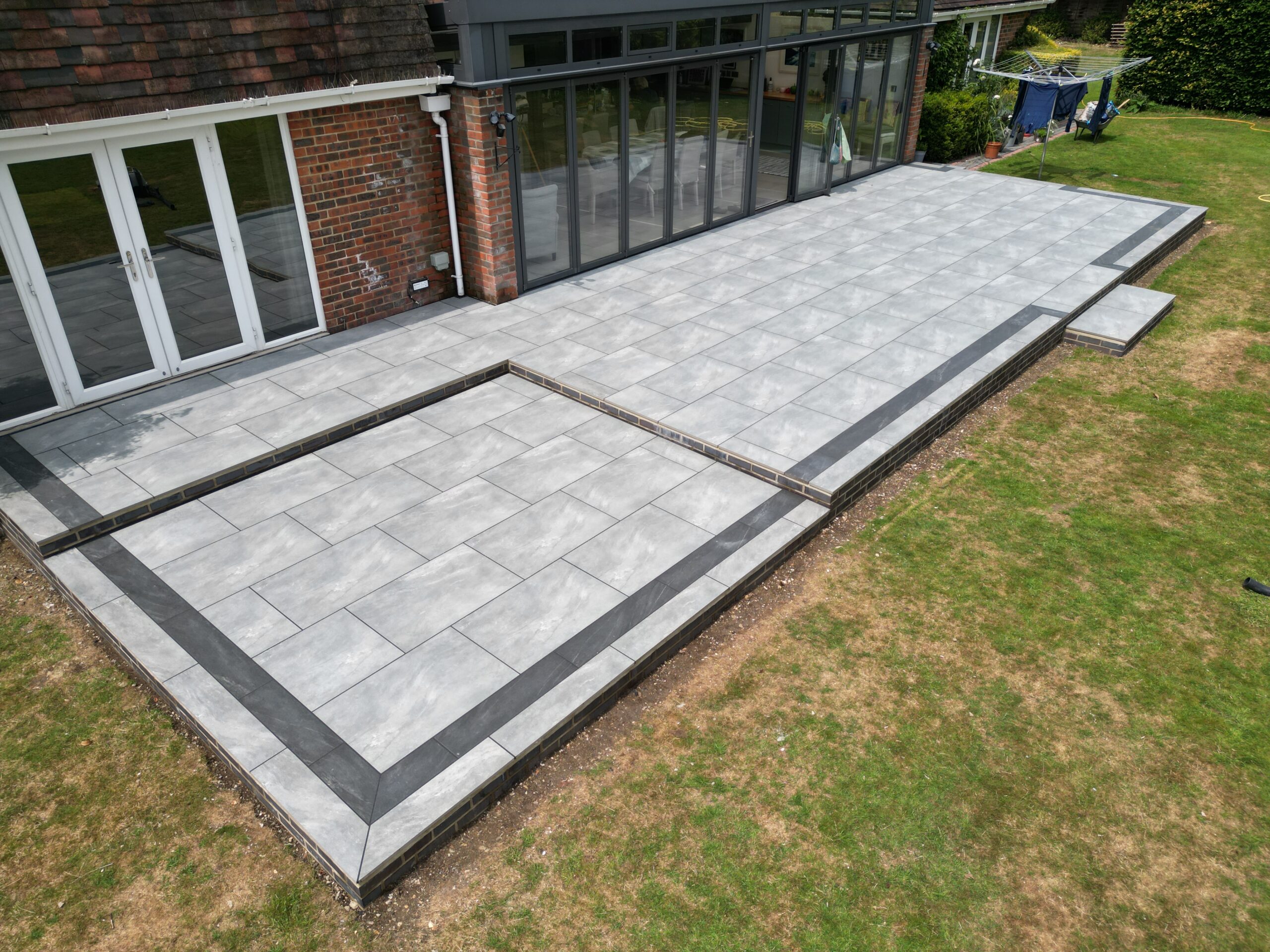 Large porcelain patio with brick retaining walls in Winchester