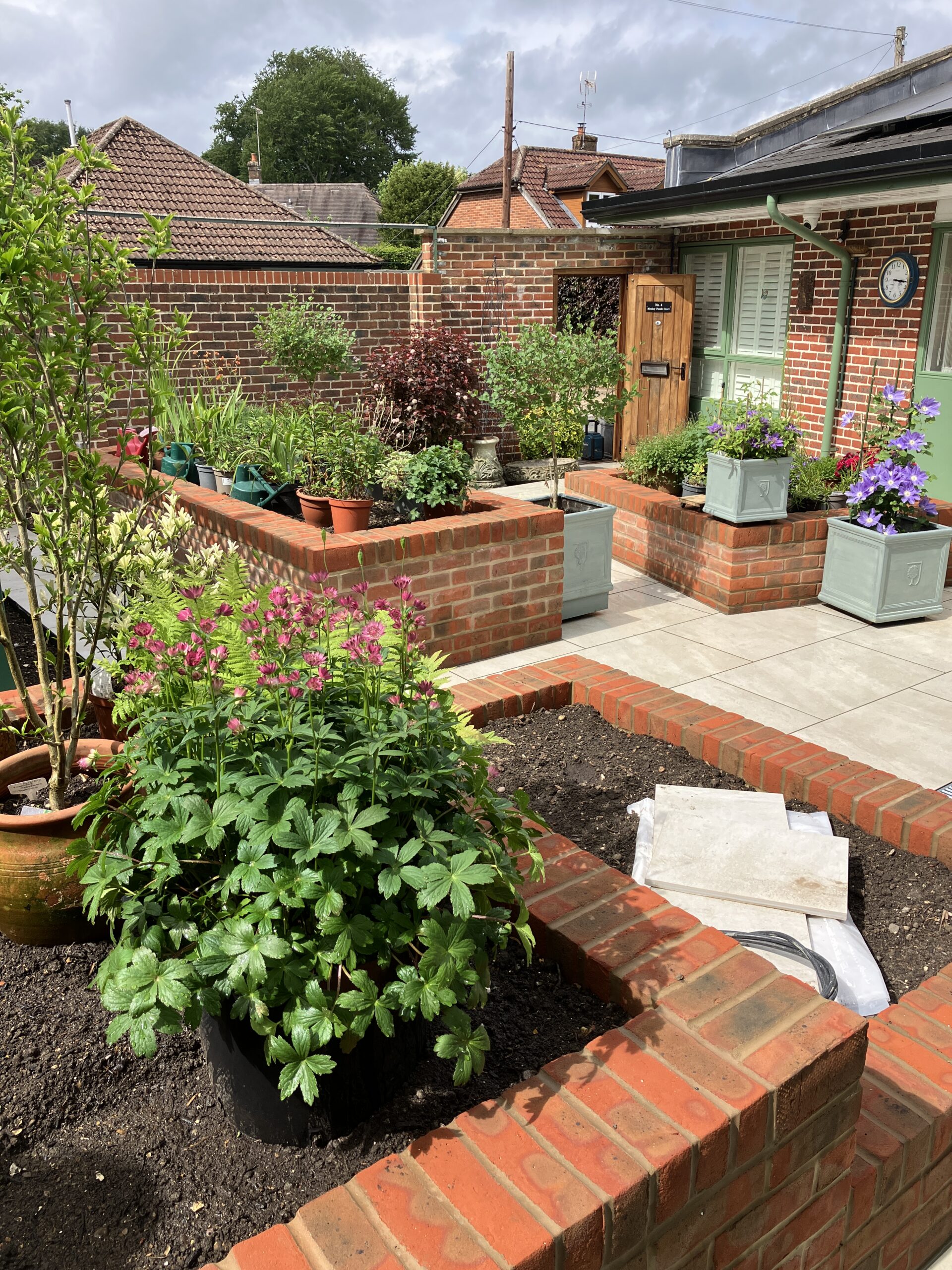 Beige porcelain paving with traditional red brick raised flower beds Winchester Beige porcelain paving with traditional red brick raised flower beds