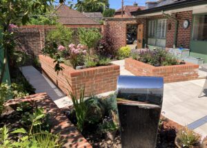 Raised red brick planting beds and beige porcelain patio in Winchester