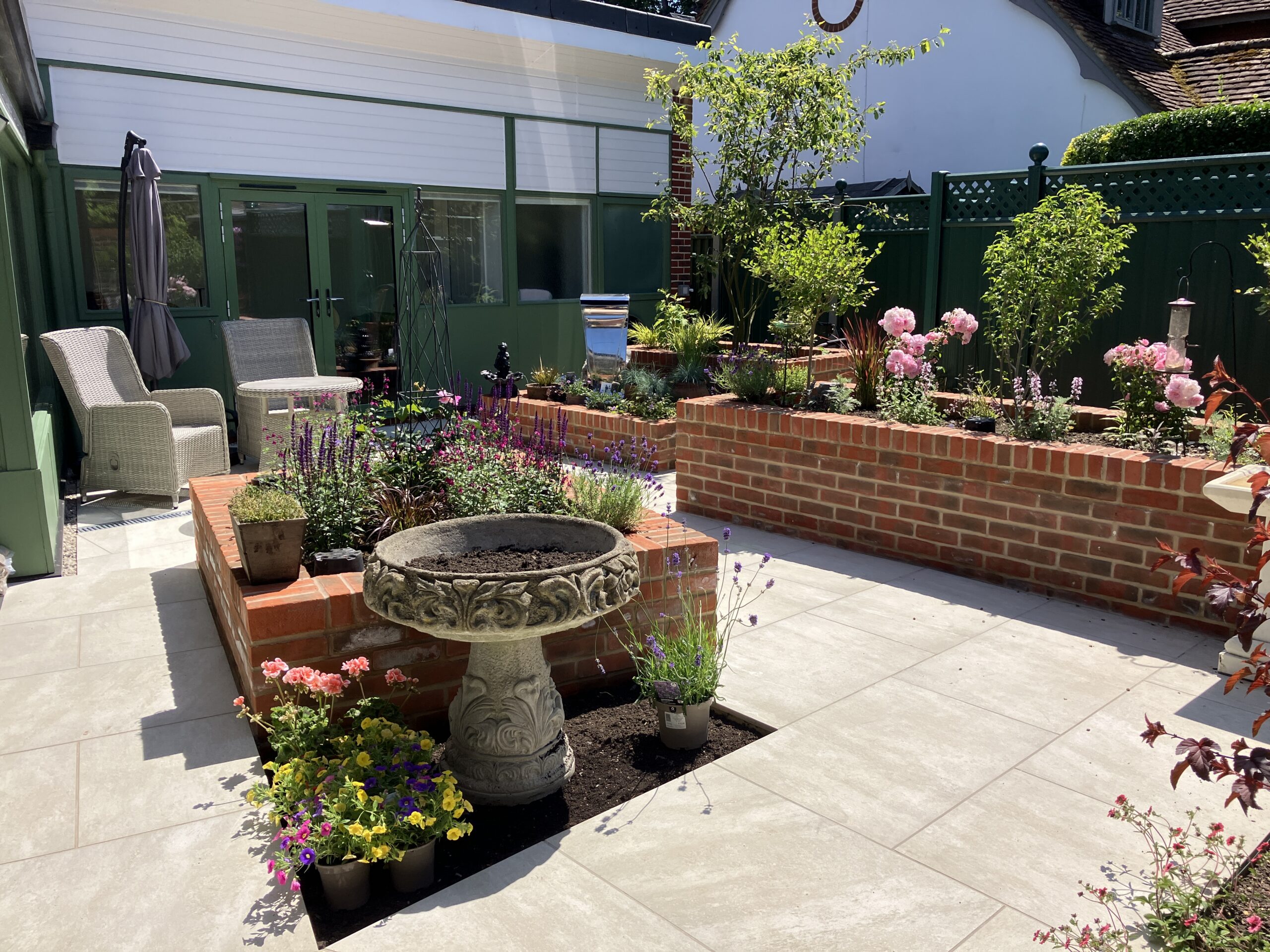 Beige porcelain paving with traditional red brick raised flower beds Winchester Beige porcelain paving with traditional red brick raised flower beds. Landscaping